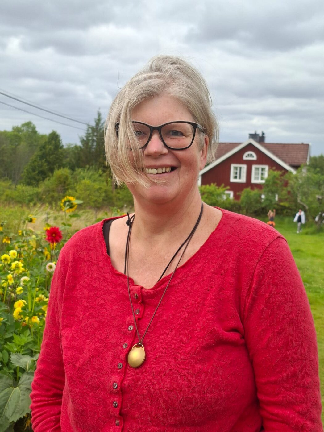 Nicola lächelt vor einem roten Schwedenhaus im Garten