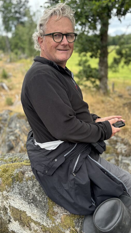 Johannes sitzt lächelnd auf dem großen Stein