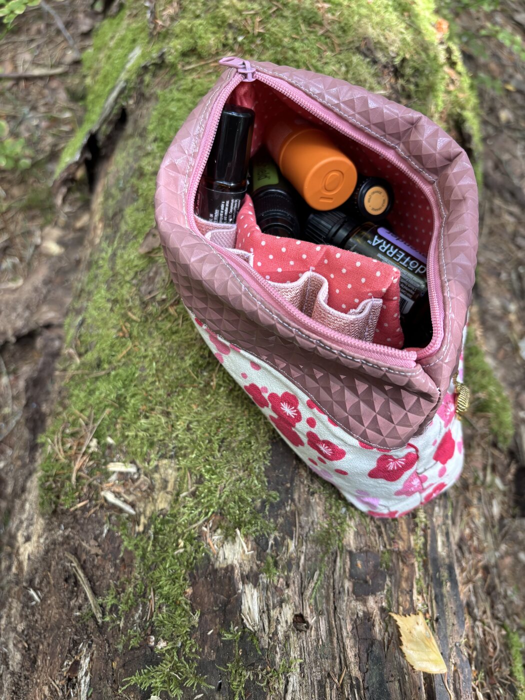 Das geöffnete Survival Pack mit den Ölen auf einem moosigen Baumstamm
