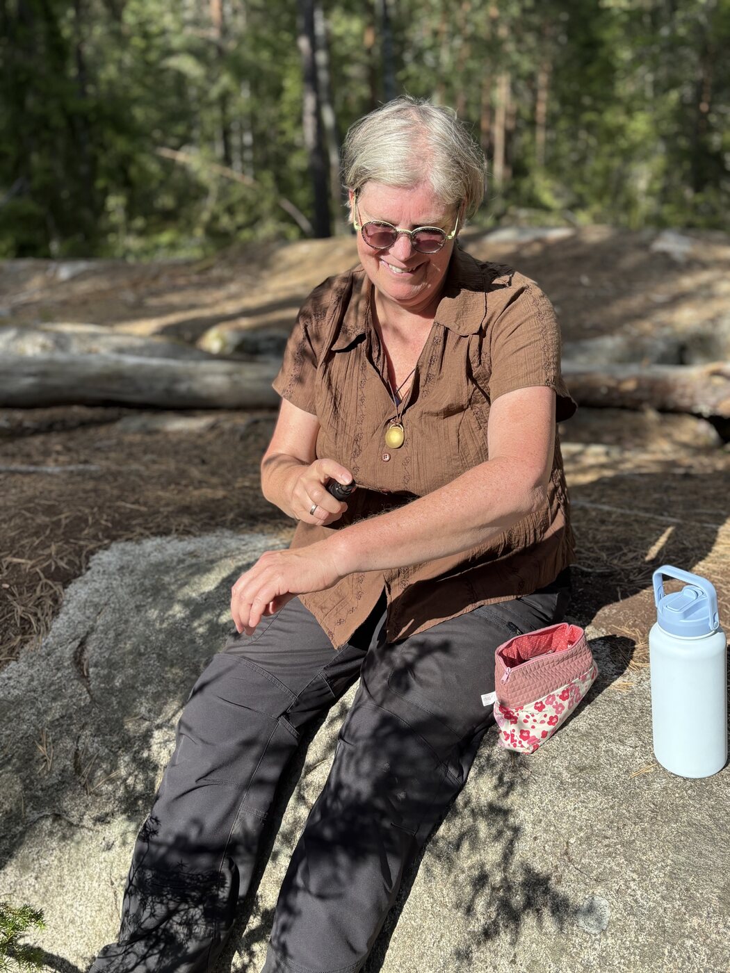 Nicola macht auf einem Felsen Pause, daneben Survival Pack und Trinkflasche