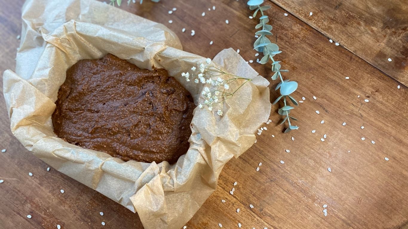 Schokoladenkuchen-Teig in einer mit Backpapier ausgelegten Form, mit Eukalyptuszweig dekoriert